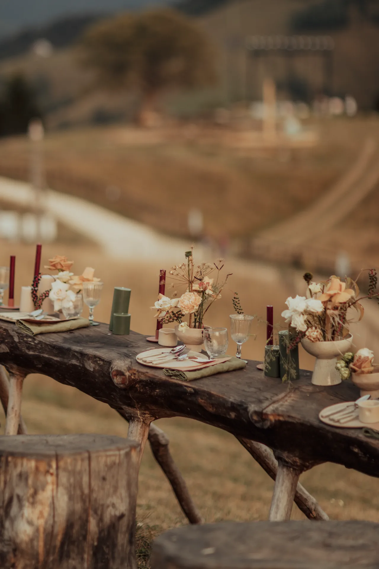 vertical-shot-wedding-table-with-floral-ceramic-arrangements-candles-cutlery-field